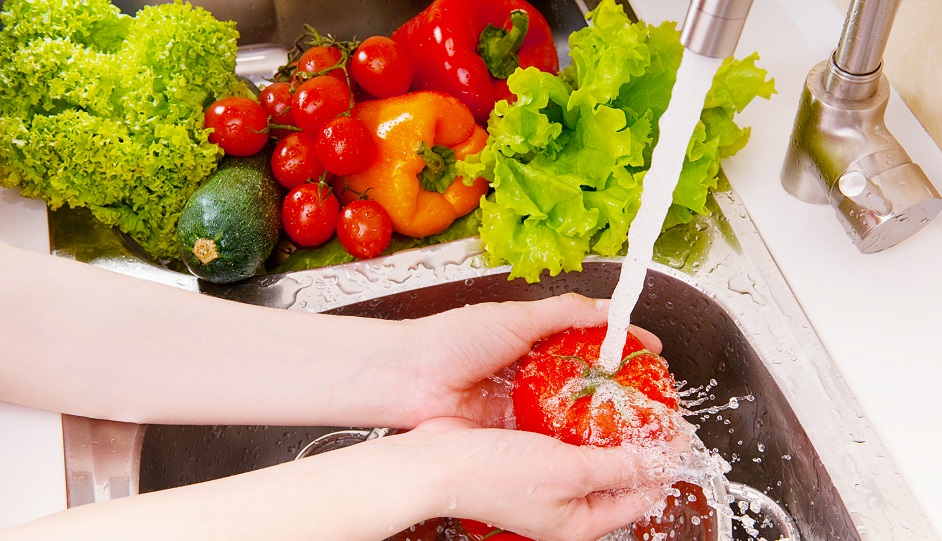 A woman washing fresh vegetables under the tap